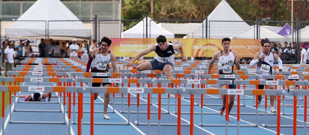 José Eduardo Aguado Peña mid-air as he jumps over a hurdle in the 110-meter race at the CONADE 2024 Nationals in Jalisco.