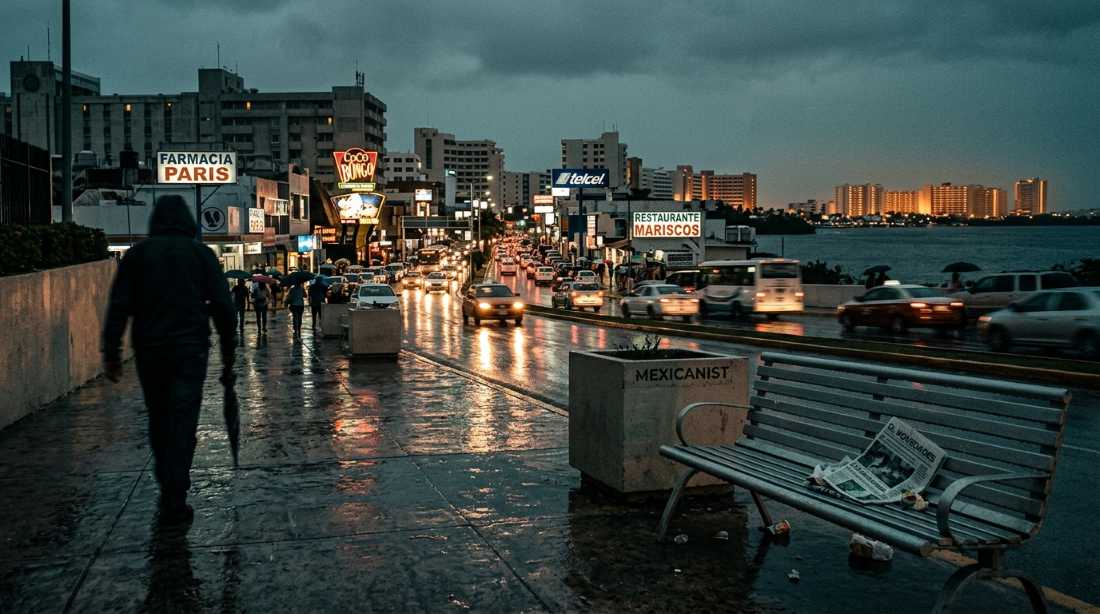 Nighttime view of Cancún's mainland streets with the Hotel Zone glowing across the lagoon, editorial photography by Mexicanist.