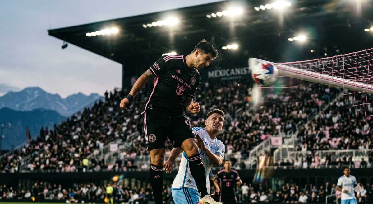 A Mexican football striker rises above a defender to score a header for Inter Miami.