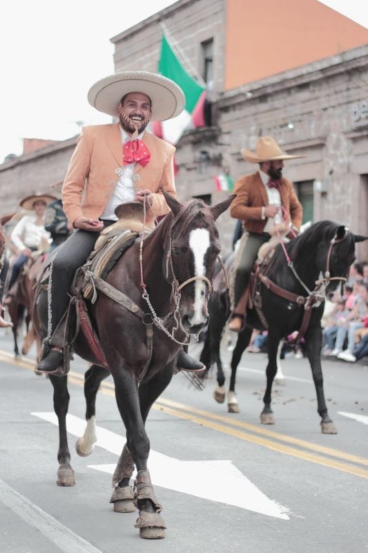 A charro dressed in traditional embroidered outfit with a wide-brimmed hat and boots.