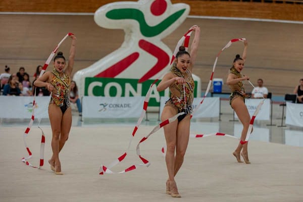 Mexican rhythmic gymnasts perform in front of judges, showcasing their skills with ribbons, hoops, and balls.