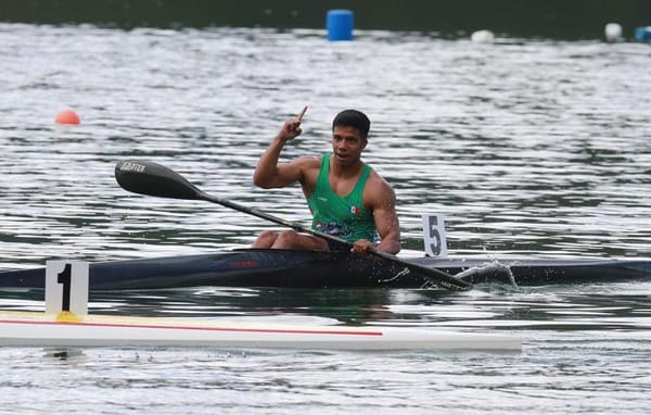 Canoe sprint race on a lake with athlete paddling towards the finish line.