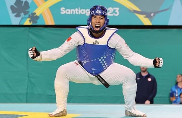 A Mexican taekwondo athlete raising his arms in triumph, wearing a gold medal.