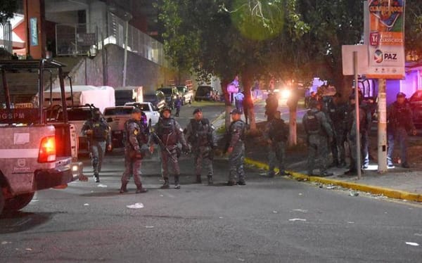 A group of police officers and investigators examining the site of an explosion.