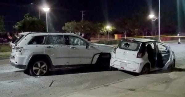 Two cars with multiple bullet holes parked on a street, surrounded by police tape and investigators..