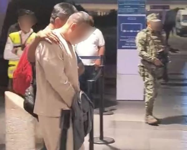 A photo of a handcuffed man being led away by police, with a blurred face to protect identity.