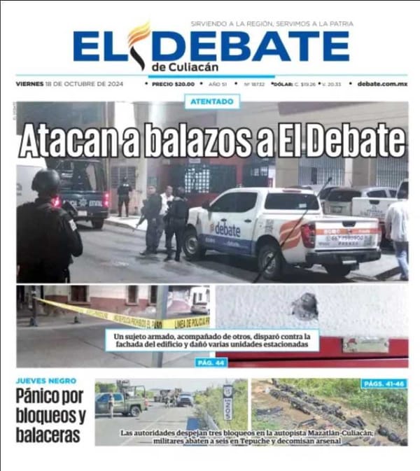 A photo of the El Debate newspaper building with bullet holes in the facade and damaged vehicles.