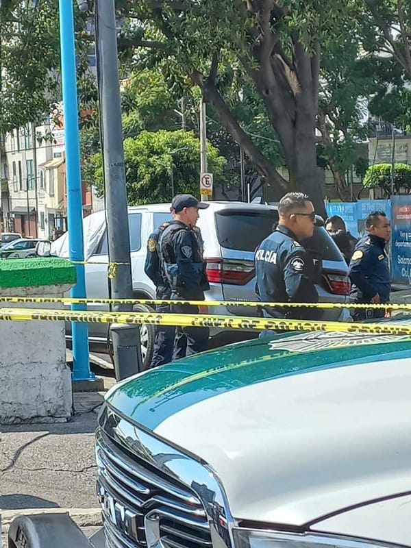 A photo of a police officer standing in front of a crime scene tape.