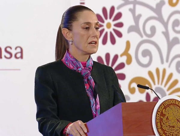 President Claudia Sheinbaum speaking at a press conference, with a serious expression.