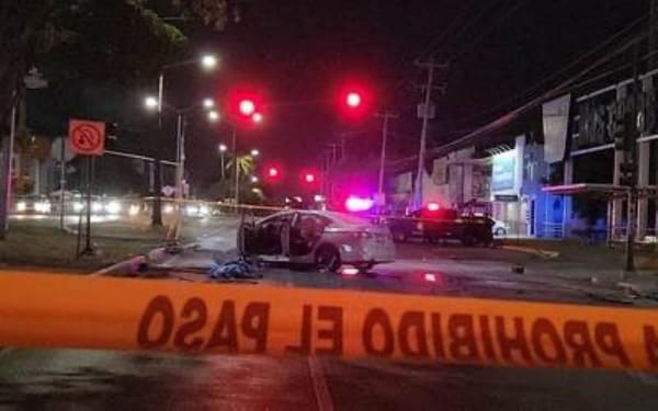 A street with a damaged car and police tape blocking off the area.