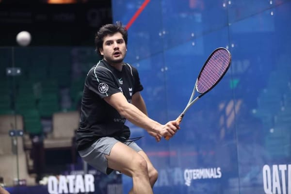 A male squash player in action, focused on hitting the ball.