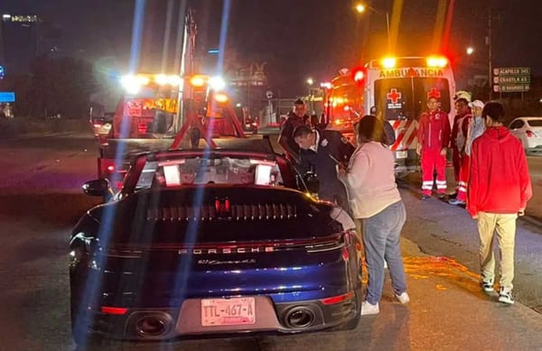 Damaged blue Porsche Carrera abandoned at night on Via Atlixcáyotl after hit-and-run accident in Puebla.