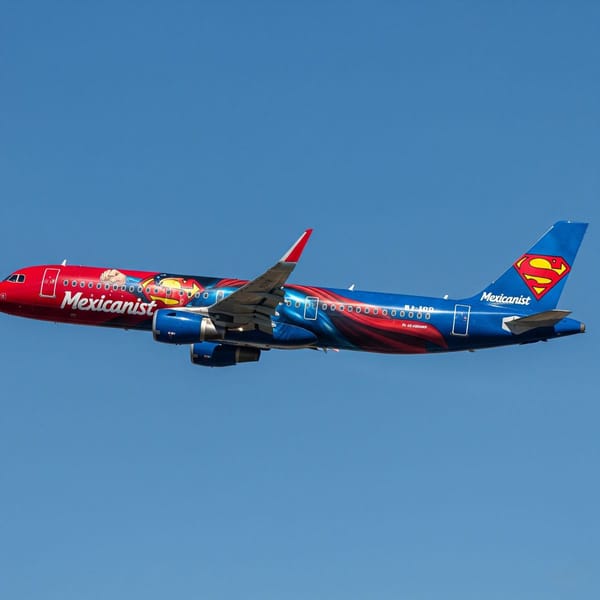 A colorful Airbus A321 airplane painted with a Superman theme, featuring the iconic red and blue colors.