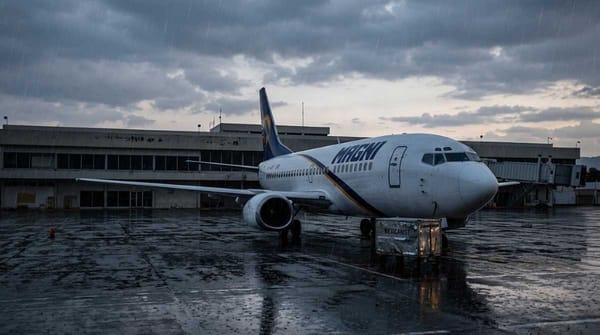 A Magnicharters Boeing 737-300 parked alone at a darkened airport gate at dusk.