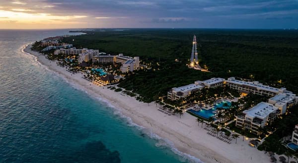 Aerial view of the Riviera Maya coastline at dusk showing resort hotels along a pristine Caribbean beach.